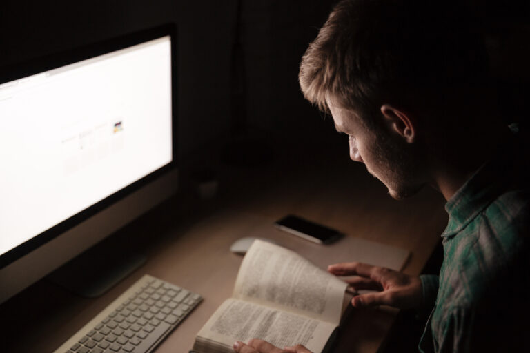 Focused Young Man Studying And Working In A Dimly Lit Room